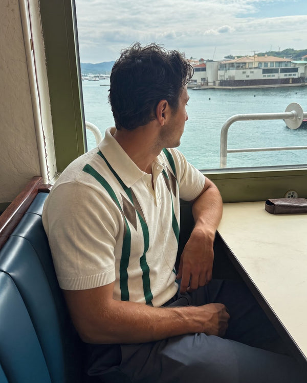 A man in a striped knit polo by the harbour