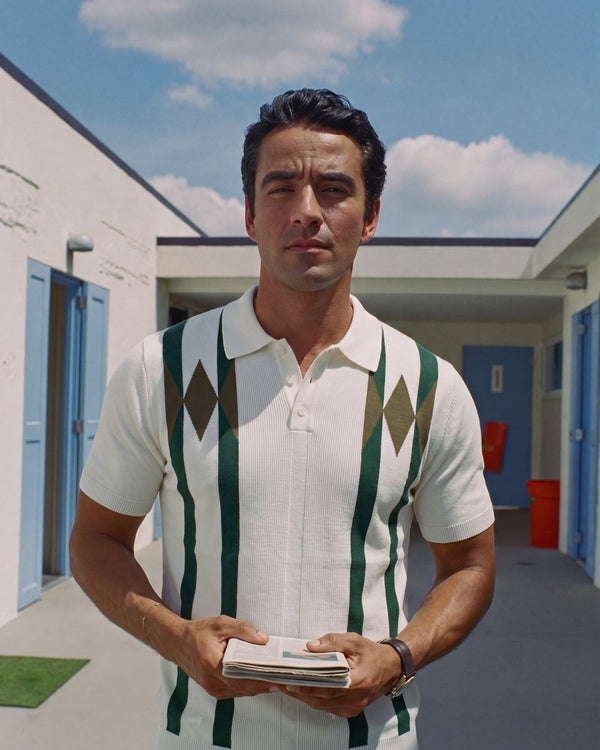A man in a patterned knit polo in a sunlit courtyard