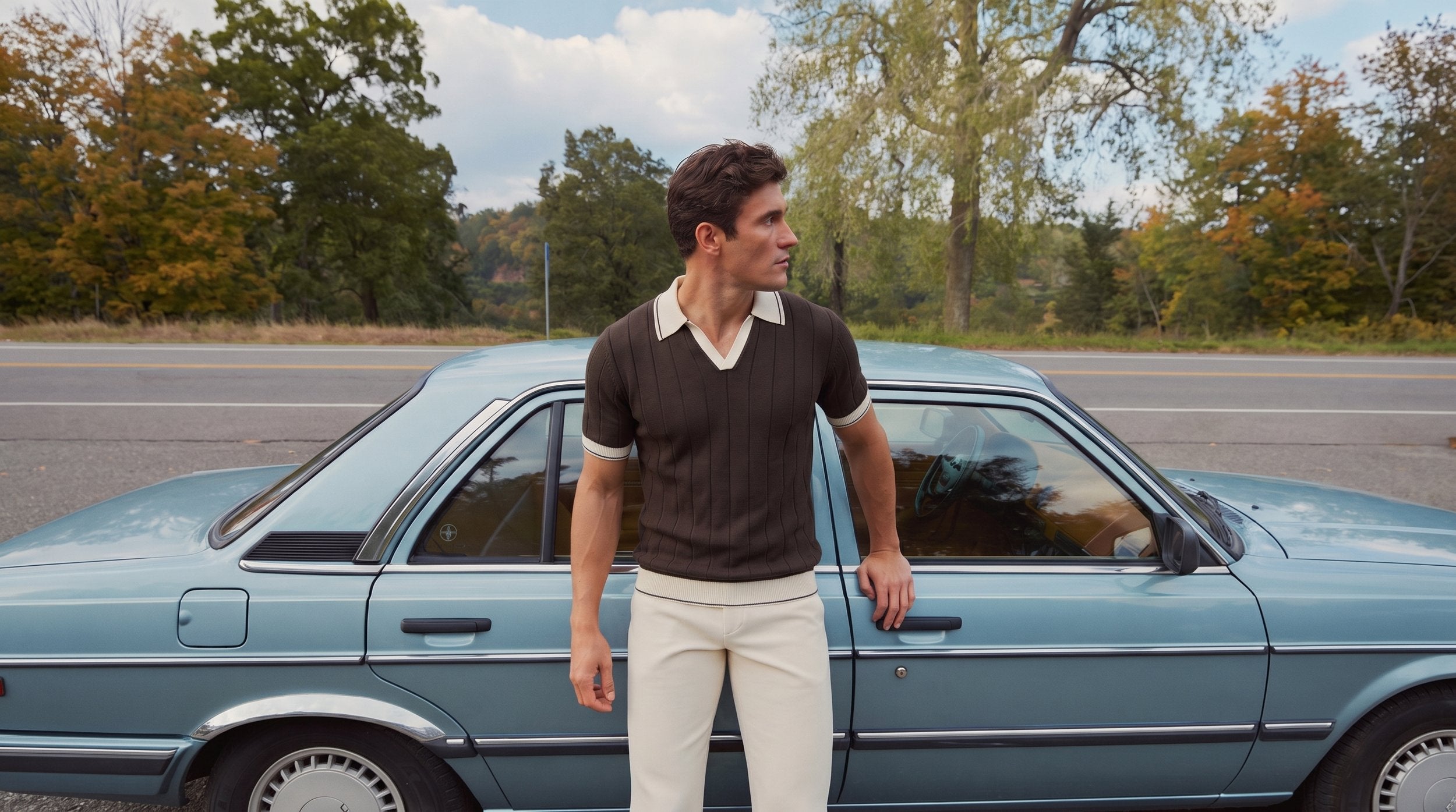 A man in a knit polo in front of a country house